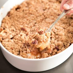 a close up of a person holding a spoon with some food in the bowl and toppings on top