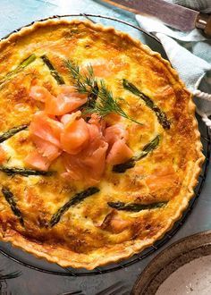 a quiche with salmon and asparagus in a pie pan on a table