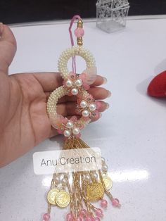 a hand holding a necklace with pearls and other jewelry items on top of a table