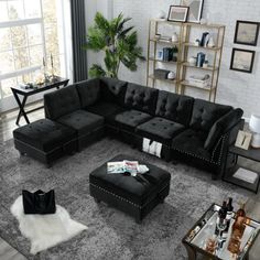 a living room filled with black furniture and lots of windows