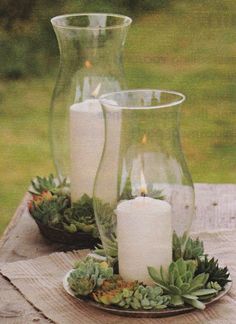 two glass vases with candles are sitting on a table