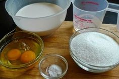 the ingredients to make an egg cake are shown in bowls on a cutting board next to measuring cups