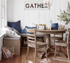 a dining room table with chairs and a bench in front of the window that reads gather