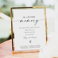 a sign that says in loving memory sitting on top of a wooden table next to a window