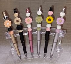 several pens are lined up in a clear container with flowers on them and one is empty