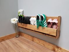 three pairs of shoes are sitting on a wooden shelf next to a vase with flowers