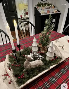 a christmas table setting with candles, ornaments and deer figurines on the centerpiece