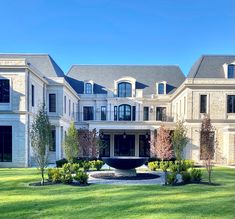 a large white house with lots of windows on it's sides and trees in the front yard