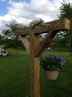 a wooden cross sitting in the middle of a lush green field next to a flower pot