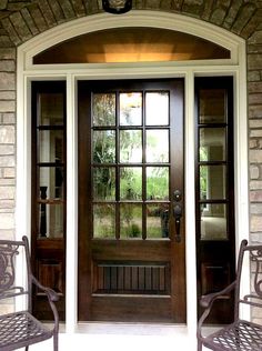 two metal chairs sitting in front of a wooden door with glass panes on it