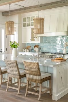 a kitchen with white cabinets and an island that has chairs around it in front of the counter