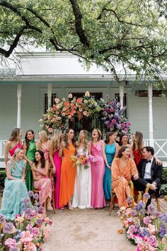 a group of women standing next to each other in front of a building with flowers