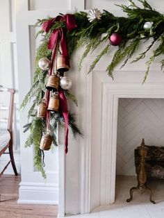 a christmas wreath with bells hanging from it's side next to a fire place