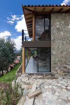 the house is made out of rocks and has glass doors that open to let in natural light