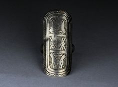 Antique silver ring composed of an oblong-shaped element depicting engraved designs with typical Tuareg geometric motifs. The front part of the ring measures 1.96 X 0.90 inch (50 x 23 mm) while the inner diameter measures 0.82 inch (21 mm). There is an antique silver mark on the backside of the ring visible in the 5th picture.  High quality silver and beautiful antique patina. Rare and collectible ring. Provenience: Mali. Ring Size (US): 12 Back to "Rings" section: https://www.etsy.com/shop/ArteOrientaleBologna?ref=hdr_shop_menu%C2%A7ion_id%C2%A7ion_id&section_id=18844837 Back to my shop: https://www.etsy.com/shop/ArteOrientaleBologna Ancient Style Engraved Silver Rings, Silver Engraved Rings In Antique Style, Silver Engraved Rings In Vintage Style, Antique Silver Rings, Geometric Motifs, Engraved Rings, X 23, Antique Silver, Statement Rings