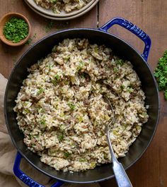 a pan filled with rice and meat on top of a wooden table