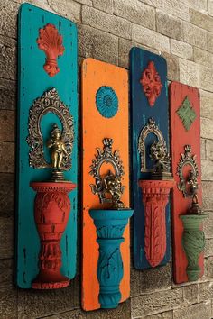 three colorful wooden wall sconces mounted to the side of a brick building, each painted different colors