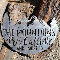 a metal sign that says the mountains are calling and i must go hanging on a tree