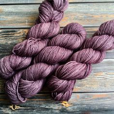 purple skeins of yarn sitting on top of a wooden table