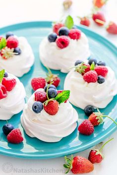 small cupcakes with whipped cream and berries on a blue plate next to strawberries