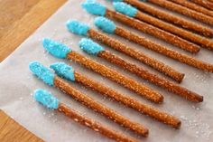 there are many pretzels with blue frosting on them sitting on wax paper