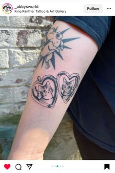 a person with a tattoo on their arm holding an open heart shaped photo frame in the shape of two cats