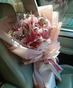 a bouquet of pink flowers sitting in the back seat of a car with ribbon tied around it