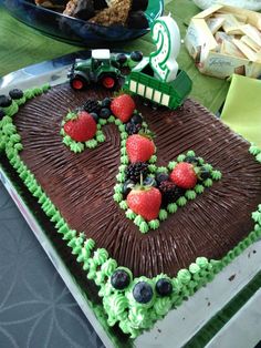 a birthday cake with chocolate frosting and strawberries in the shape of a tractor