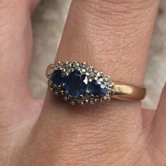 a woman's hand with a gold ring and two blue stones on the band