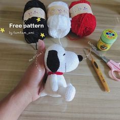 a hand holding a stuffed dog next to crochet supplies