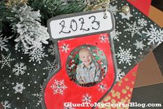 a christmas ornament hanging from a tree with snowflakes and evergreens