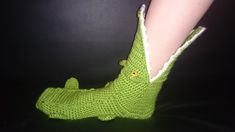 there is a crocheted green alligator slipper on someone's feet