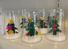 three clear glass containers with christmas decorations in them on top of a white countertop