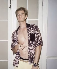 a man standing in front of a door with his shirt open and no shirt on