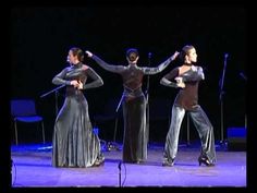 three women are performing on stage with their hands in the air and one woman is holding her arms out