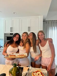 four girls in the kitchen posing with pizza