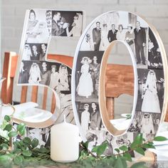 a wooden table topped with photos and greenery next to a white candle on top of a