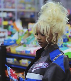 a woman with blonde hair standing in front of a store display filled with candy bars