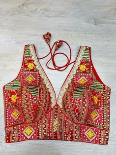 Red multicolored embroidered sleeveless blouse features thread & mirror work, hook closure & tie-up at the back. Team this blouse with a contrasting saree to look gorgeous and create a stunning and beautiful look. Buy this designer blouse in the USA from Pure Elegance. Disclaimer: The actual product may vary slightly from the image. These are custom orders, hence expect slight variation in color, and placement of the motif, or buta. ESTIMATED DELIVERYBecause this is a custom order, it would take about 2 weeks from the date of purchase. RETURN POLICY: This product is a custom order and cannot be returned or exchanged. Blouse With Mirror Work, Suits Indian, Mirror Embroidery, Sharara Suits, Embroidered Sarees, Fashion Journals, Pure Elegance, Traditional Fabric, Dresses Designer