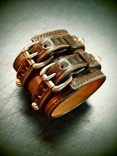 "This brown leather cuff uses natural vegetable-tanned leather and is Hand tooled,scribed,edged,studded and stamped with an original border design. Antiqued silver concho spots run 2 straps over the main cuff. I use Western techniques and no electric tools. It is finished in vintage walnut dye, distressed and hand rubbed creating a unique vintage look. Aged brass buckles and vintage copper rivets provide the closure I'll need your wrist size for this cuff! I Can size it for men or women Instruct Punk Style Studded Leather Bracelet, Punk Leather Bracelet With Studs, Punk Leather Cuff Wristband, Vintage Leather Bracelet With Rivets, Rustic Leather Cuff Bracelet With Leather Strap, Vintage Leather Wristband With Leather Strap, Rustic Leather Concho Bracelets, Western Style Hand Tooled Leather Bracelets, Rustic Leather Cuff Bracelet