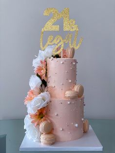 a pink and gold cake with flowers on the top is decorated with a 21st century sign