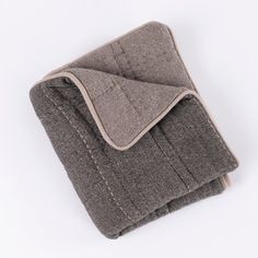 a blanket folded up on top of a white surface with a gray and beige design