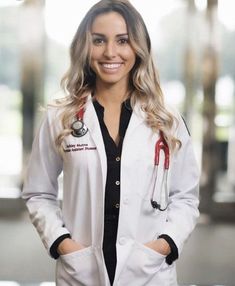 a woman in white lab coat standing with her hands on her hips and smiling at the camera