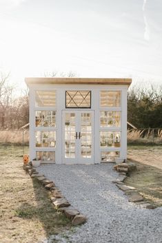 a small white building sitting in the middle of a field