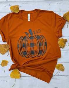 Plaid Pumpkin tee. Your choice of color for shirt.  Shirt is unisex and is true to size. Measurements in picture along with color options.  This soft bella canvas brand tee, baby-knit t-shirt looks great &  it fits like a well-loved favorite. Made from 100% cotton, except for heather colors, which contain polyester. I recommend washing inside out in cold water and tumble dry or air dry on low heat. Bella Canvas shirts have been hard to get in certain colors. If Bella Canvas is not available, you will get a different brand soft style tee. Trendy Fall Short Sleeve T-shirt, Trendy Short Sleeve Fall T-shirt, Trendy Short Sleeve T-shirt For Fall, Short Sleeve T-shirt With Screen Print For Fall, Trendy Fall Short Sleeve Shirt, Trendy Short Sleeve Fall Shirt, Trendy Graphic Print Shirt For Fall, Casual Screen Print Shirt For Fall, Orange Letter Print T-shirt For Fall