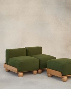 a green couch and footstool sitting next to each other in front of a wall