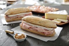 a sandwich with meat and cheese sitting on top of paper next to some condiments