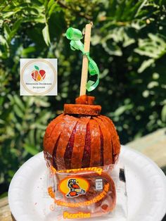 a paper plate with an orange pumpkin shaped cake on it and a stick sticking out of the top