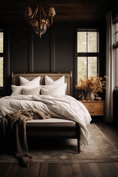 a bed with white sheets and pillows in a dark room next to two large windows