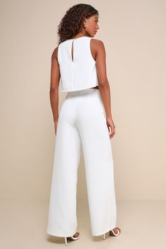 Sophisticated and flirty, the Lulus Timeless Disposition White Wide-Leg Two-Piece Jumpsuit will never go out of style! This impressive two-piece jumpsuit has a crepe woven fabrication that shapes a crop top with a crew neckline and a darted bodice with a top button closure and a keyhole-style cutout at the back. The matching pants have a high-waisted fit, darted details, and wide pant legs that fall to ankle-length hems. Pants have a hidden zipper/clasp at back. Fit: This garment fits true to si White Sleeveless Pantsuit For Night Out, Chic Two-piece Wide Leg Jumpsuits And Rompers, Chic Two-piece High Waist Crop Top, Chic Solid Color Two-piece Jumpsuit And Romper, Chic Two-piece Spring Pantsuit, Chic Two-piece Summer Pantsuit, Elegant Fitted Two-piece Jumpsuits And Rompers, Chic Two-piece Pantsuit For Party, Chic Two-piece Jumpsuit For Night Out